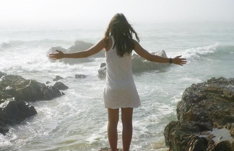 Женщина стоит на скалистом берегу